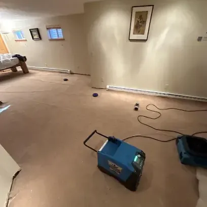 A finished basement with the carpet pulled up and drying equipment running on the bare floor