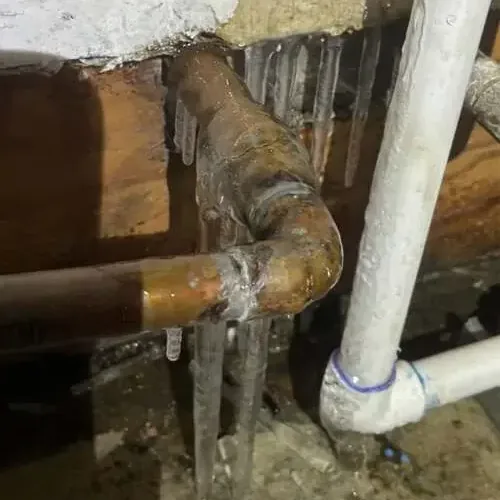 Ice coating copper and plastic supply pipes along a cold basement ceiling