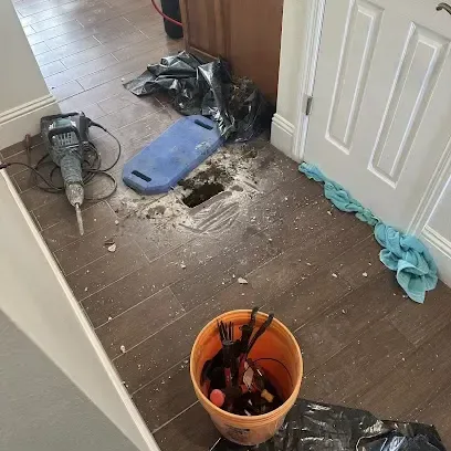 Floor tile cut open to expose a leaking pipe in a concrete slab